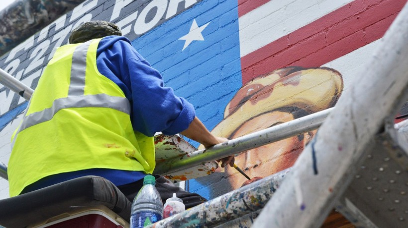 Joe Bravo touches up the portraits int he center of the mural.